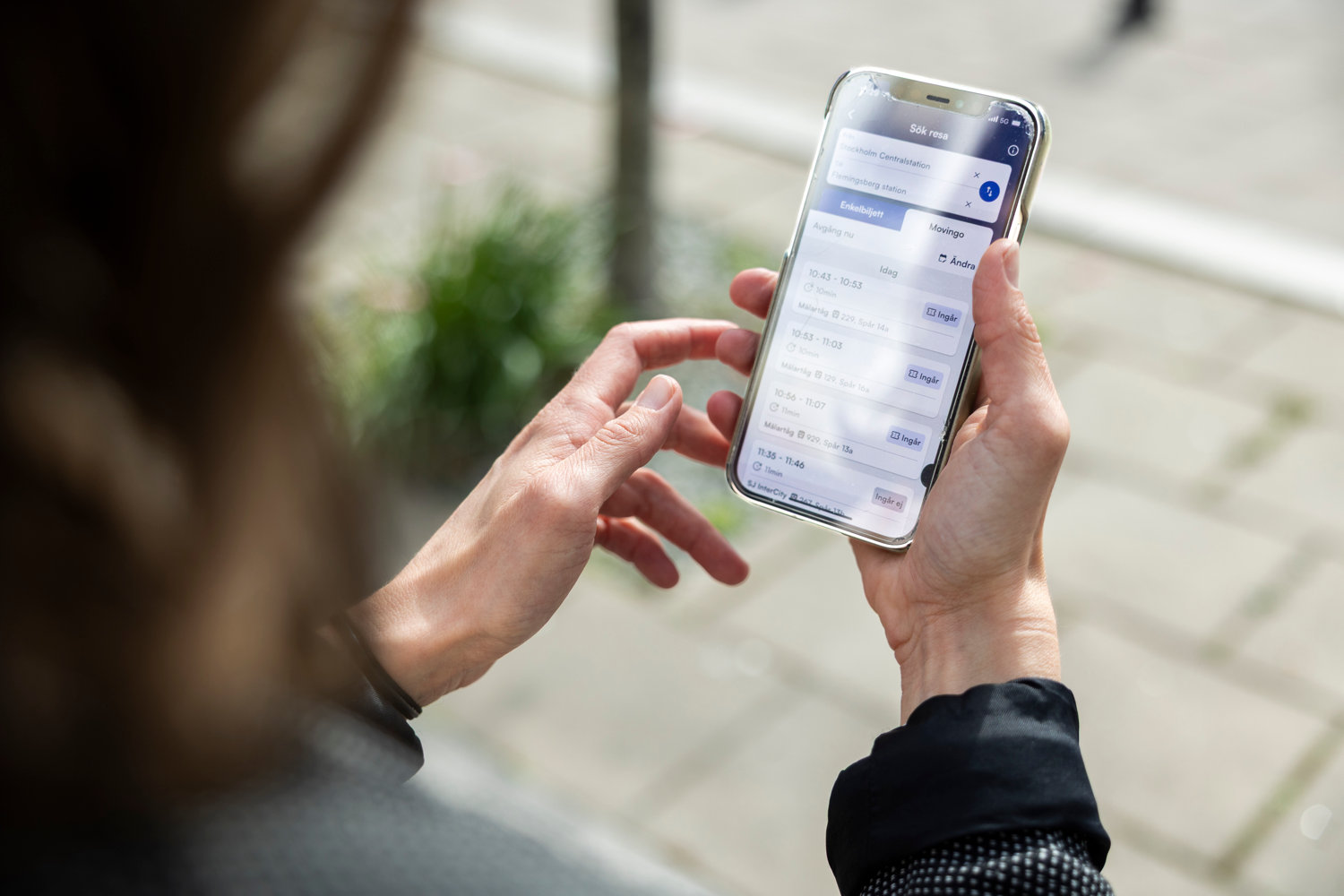 person som tittar på sin mobiltelefon med Mälartågs app