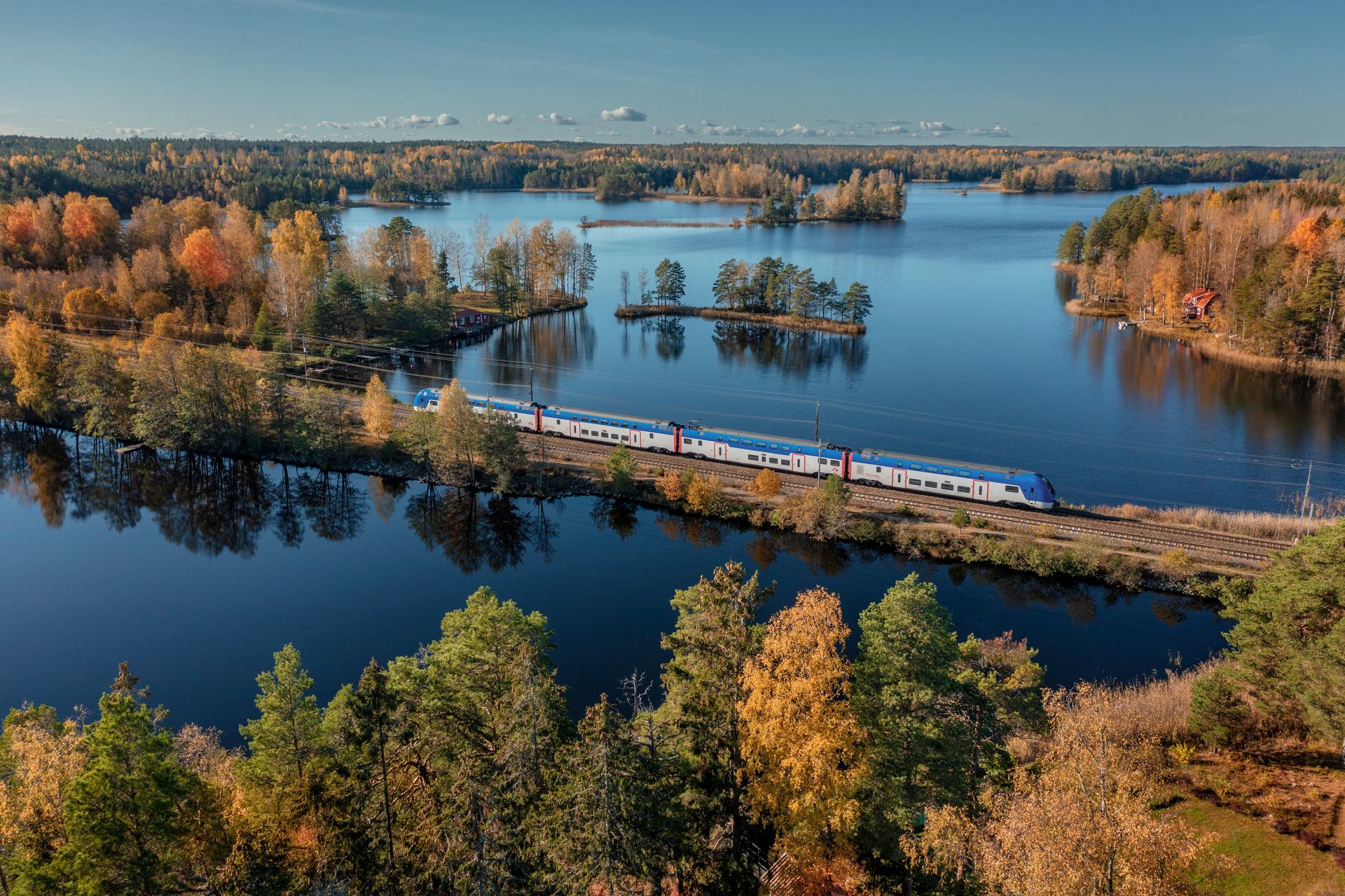Ett Mälartåg som åker vid vatten i ett höstlandskap