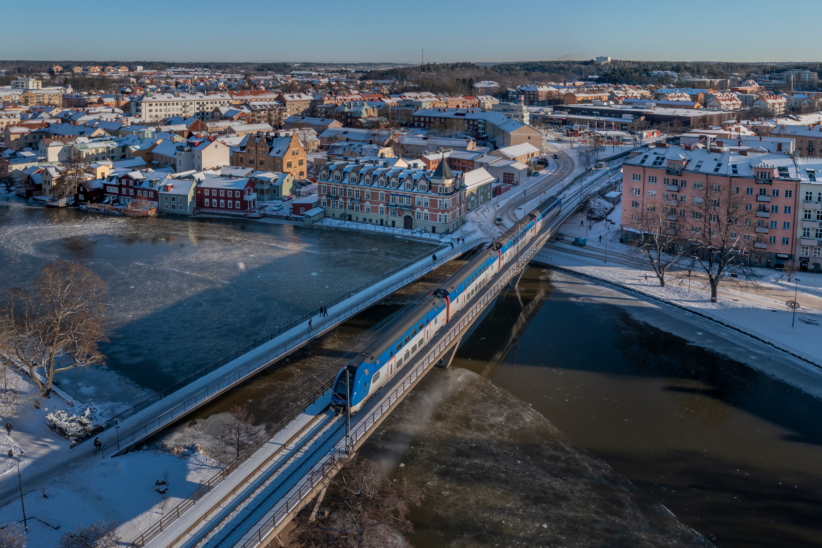 Ett mälartåg på en bro ovan vatten i vinterlandskap vid eskilstuna