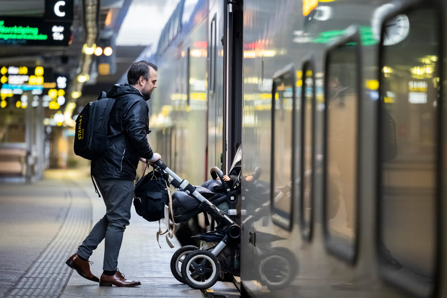 man som går ombord på ett Mälartåg med en barnvagn