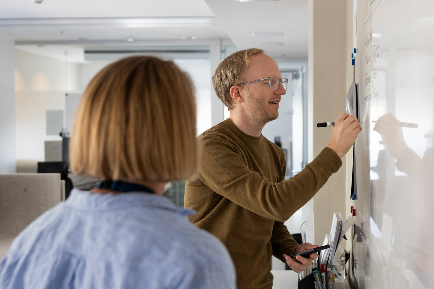 man som skriver på whiteboard och en kvinna som står i förgrunden
