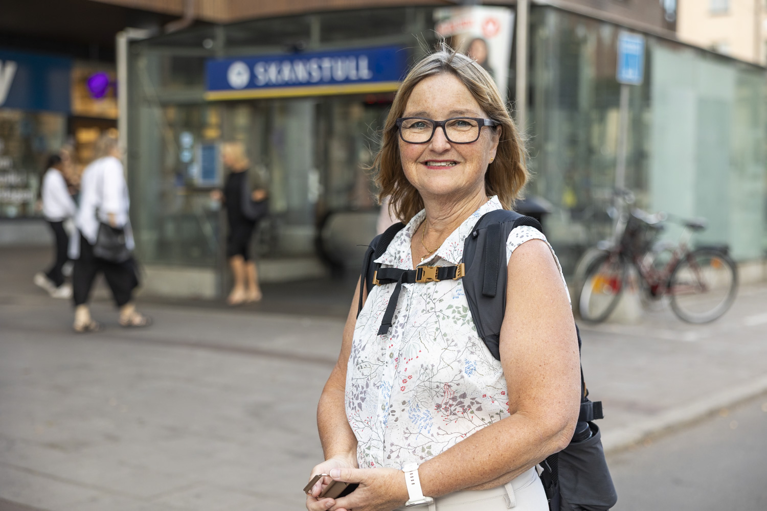 Kvinna som tittar in i kameran och står framför en tunnelbaneuppgång i stockholm