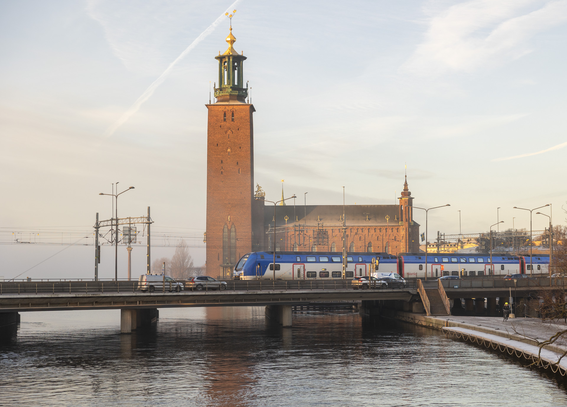 Stockholm City Hall with its tower in the background and a Mälartåg train on the bridge in front.