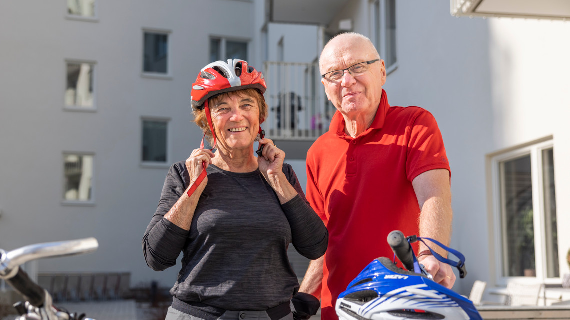 En man och en kvinna  står bredvid sina cyklar med sina hjälmar