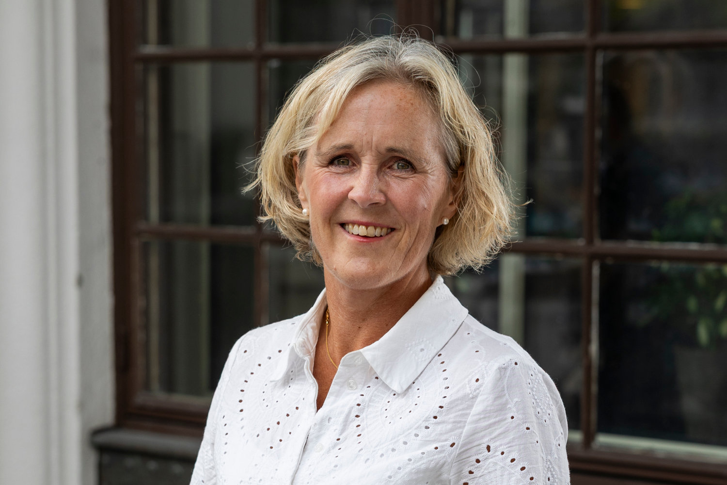 Kvinna i vit blus som kollar in i kameran