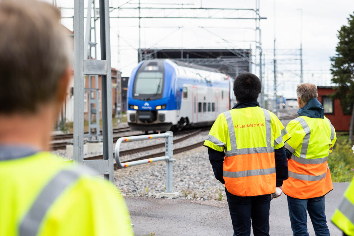 Två personer i varselväst som tittar på ett Mälartåg som rullar in till depån i Gredby