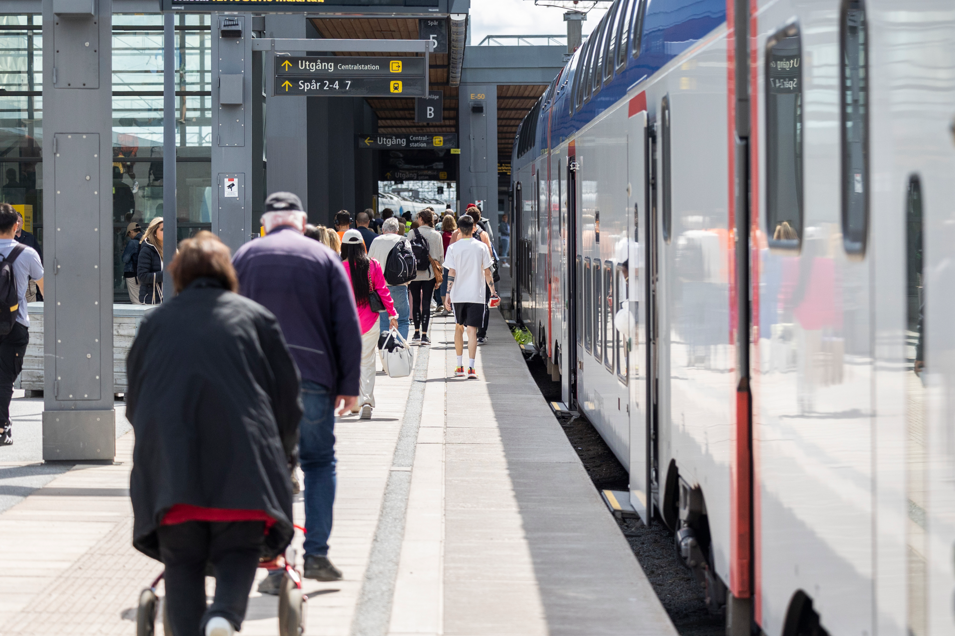 Resenärer som går bredvid ett mälartåg på Uppsala station